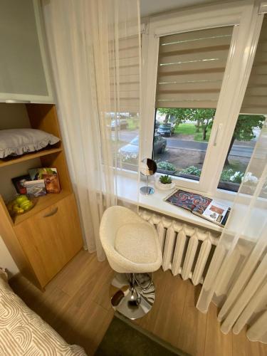 a bedroom with a white chair and a window at Acapulco Liepaja in Liepāja