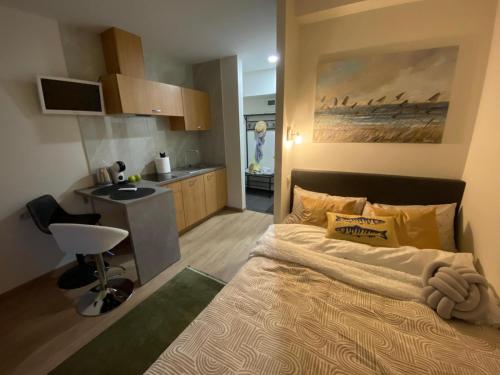 a bedroom with a large bed and a kitchen at Acapulco Liepaja in Liepāja