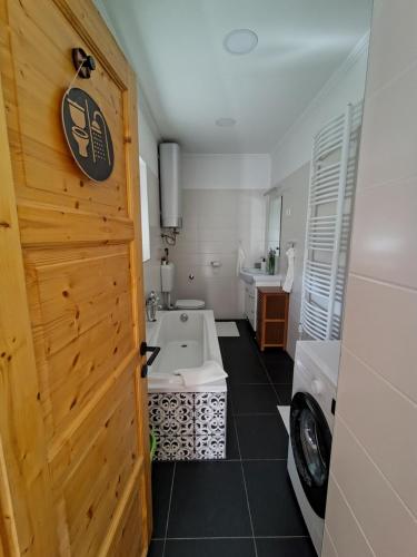 a bathroom with a tub and a sink and a door at Vén Malom Apartman in Zalaszentgrót