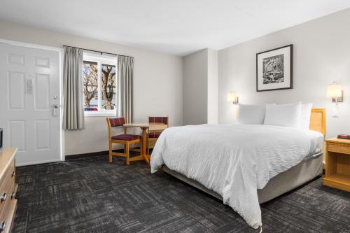 a hotel room with a bed and a table at The Lodge at Arrow Lakes in Nakusp