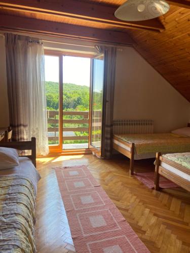 a bedroom with two beds and a large window at House Draga Plitvice near the lakes and bus stop in Plitvička Jezera