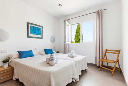 two beds in a white room with a window at Villa Verano in Cala Galdana