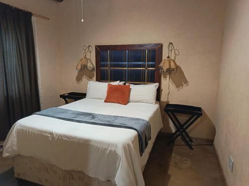 a bedroom with a large bed with white sheets and orange pillows at Hazyview Country Cottages in Hazyview