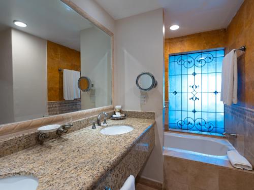 a bathroom with two sinks and a tub and a window at Las Villas Hotel & Golf By Estrella del Mar in Mazatlán