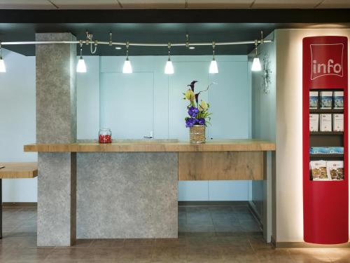 a counter in a store with a red refrigerator at ibis Lyon Sud Saint-Rambert-d'Albon in Saint-Rambert-dʼAlbon