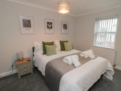 a bedroom with two beds with white sheets and green pillows at 3 Railway Terrace in Bridlington
