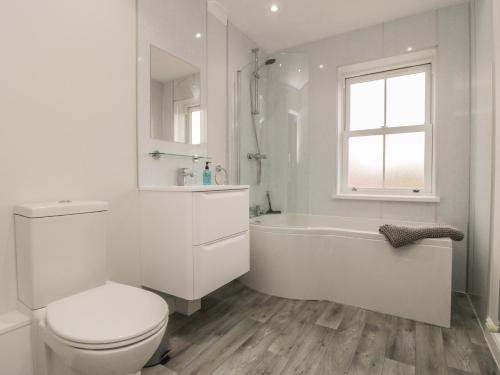 a white bathroom with a toilet and a tub and a window at 3 Railway Terrace in Bridlington