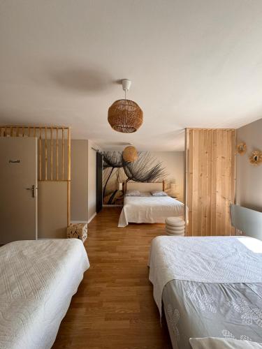 a bedroom with two beds and a chandelier at Les Chambres du Clos De L'église in Senozan
