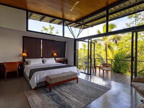 a bedroom with a large bed and large windows at BlackRoots Unawatuna in Unawatuna
