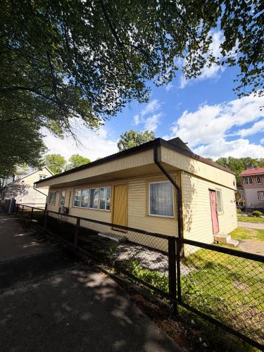 a small yellow house with a fence around it at Sadama Hostel & Caravan Camping in Pärnu