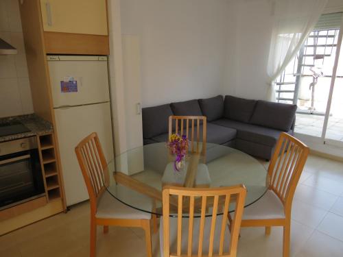 a kitchen with a glass table and chairs and a couch at Apartamento Tres Ce in Alcossebre