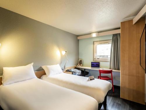 a room with two beds and a desk with a computer at Ibis Bourges Centre, Hôtel Restaurant in Bourges