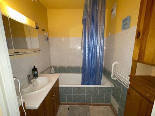 a bathroom with a sink and a tub and a shower curtain at Appartement Mona Lisa in Ris-Orangis