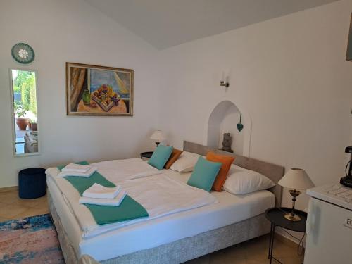 a bedroom with a large white bed with colorful pillows at Csopak Mariann Apartman in Csopak