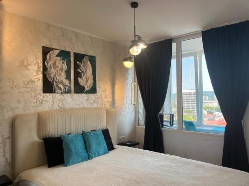 a bedroom with a bed with blue pillows and a window at Balkan tower REST 2 Безплатно паркомясто in Gabrovo