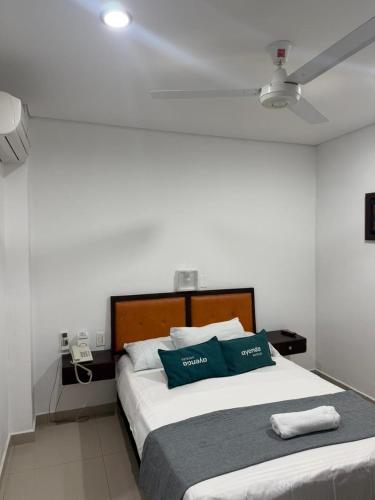 a bedroom with a large bed with two blue pillows at Hotel LHM in Montería
