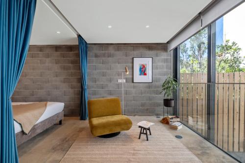 a bedroom with a bed and a yellow chair at The 21 by Homie in Ribeira Brava