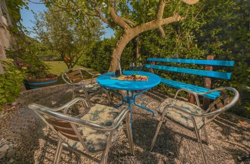 a blue table with three chairs and a blue bench at Green Oasis Residence in Radanovići