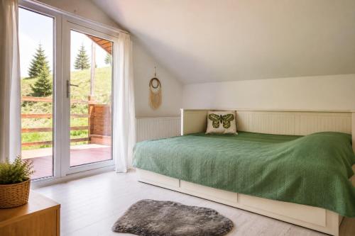 a bedroom with a green bed and a large window at La Poalele Cerului in Fundata