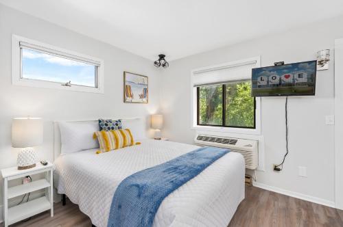 a white bedroom with a bed and a tv at Assateague Inn 100-2R in Chincoteague