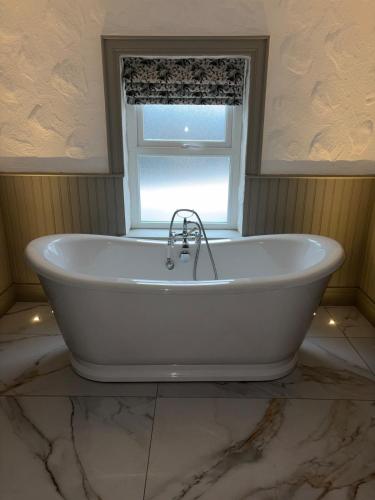 a bath tub in a bathroom with a window at Hughie Toms Cottage in Greencastle