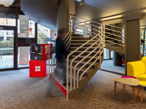 a person walking down a staircase in a building at ibis Epernay Centre Ville in Épernay