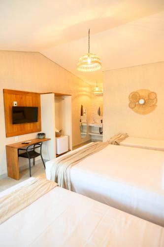 a hotel room with two beds and a desk at Desfrute Pousada e Experiencia in Arraial d'Ajuda