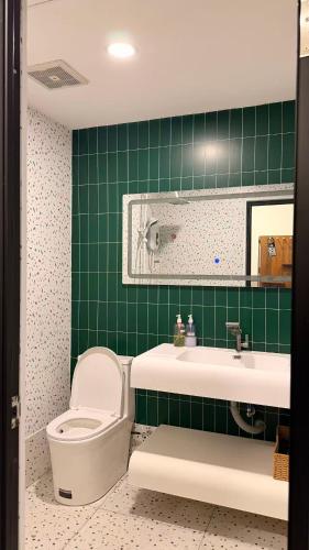 a green tiled bathroom with a toilet and a sink at THE SWAN loft in Sibu