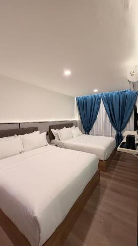 two beds in a room with blue curtains at THE SWAN loft in Sibu