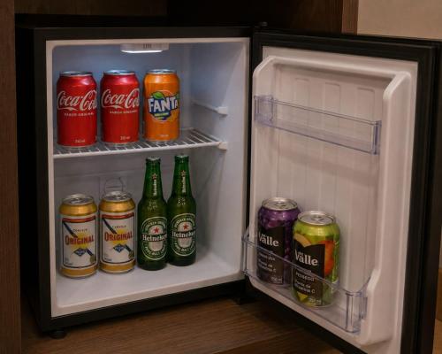 an open refrigerator with drinks and cans of soda at Pousada Yeshua in Paracatu