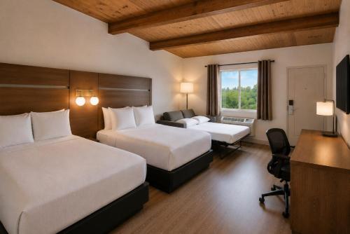 a hotel room with two beds and a desk at Ramada by Wyndham 1000 Islands Gananoque in Gananoque