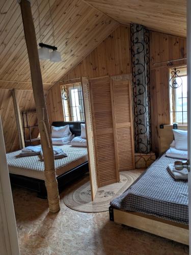two beds in a room with wooden walls at Яблунева садиба in Demidovka