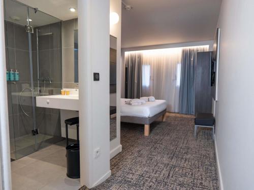 a bathroom with a sink and a bed and a mirror at Novotel Toulouse Centre Compans Caffarelli in Toulouse