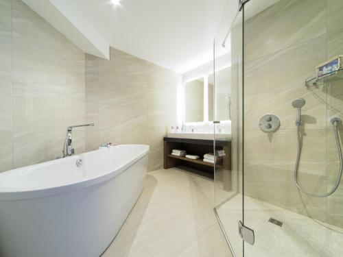 a bathroom with a tub and a glass shower at ibis Styles La Rochelle Centre Vieux Port in La Rochelle