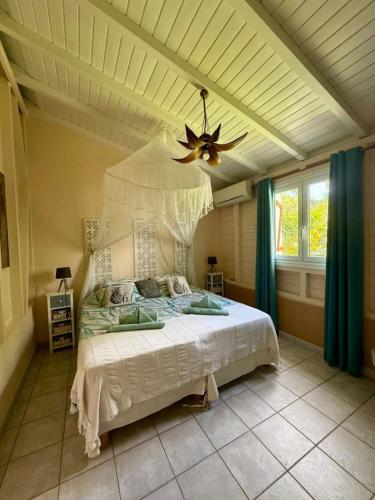 a bedroom with a white bed with a ceiling at Villa Ti Gîte - Piscine privée in Le Marin