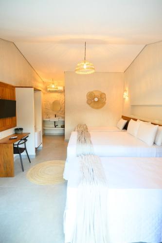 a hotel room with two beds and a desk at Desfrute Pousada e Experiencia in Arraial d'Ajuda