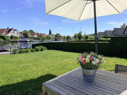 a bucket of flowers sitting on a table with an umbrella at Villa Water en Meer in Terherne