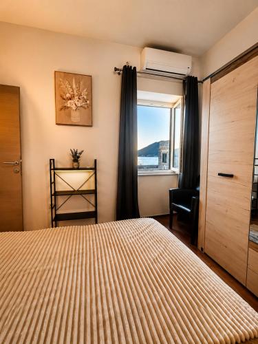 a bedroom with a bed and a window with a chair at Apartments Klara in Donja Lastva