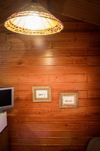 a chandelier hangs above two pictures on a wooden wall at Camping Oleiros in Oleiros