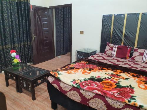 a room with two beds and a table and a door at New aalbayan hotel in Lahore