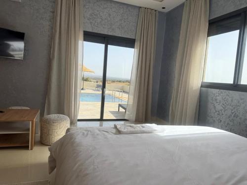 a bedroom with a bed and a view of a pool at Villa neuve pour un séjour agréable à Essaouira in Essaouira