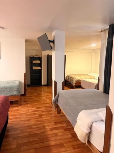a room with two beds and a flat screen tv at Artezana Hotel in Cusco