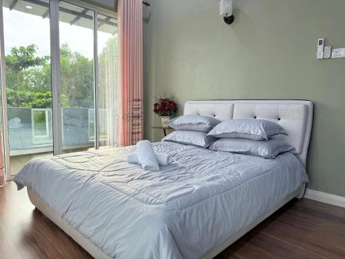 a white bed with pillows in a bedroom with a window at Teratak Chena - Lux Bungalow in Kuala Terengganu