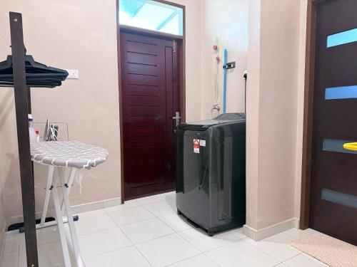a room with a tv and a stool and a door at Teratak Chena - Lux Bungalow in Kuala Terengganu