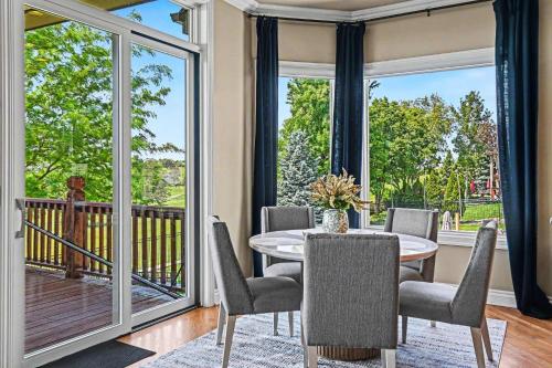 a dining room with a table and chairs and large windows at Mulligan Manor Golf Course Views Fun Amenities in Omaha