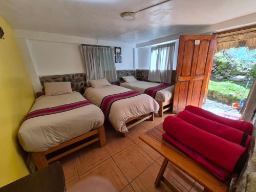 ein Zimmer mit drei Betten und einem roten Sofa in der Unterkunft Nacho's hotel in Soray