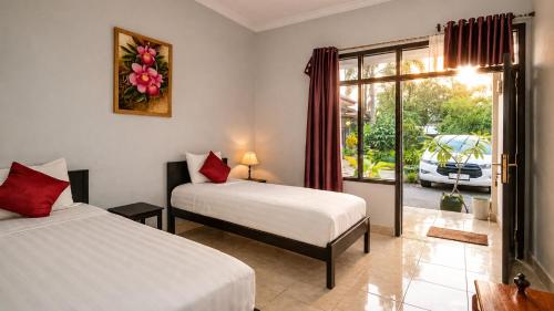 a bedroom with two beds and a door to a patio at Cahaya Adrian Hotel in Labuan Bajo