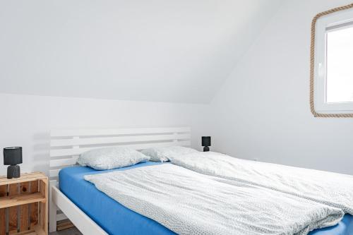 a white bedroom with a blue bed and a mirror at Domki Anchor - Rodzinne Domki - Cisza i Spokój in Lubiatowo