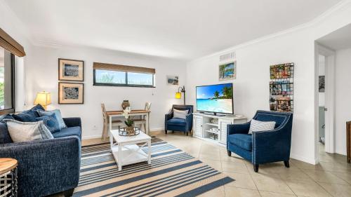 a living room with two blue chairs and a tv at ON The Beach Juno! Modern Lux Seaside! in Juno Beach