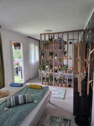 a bedroom with a bed and a room with potted plants at La Moșie in Săldăbagiu de Munte